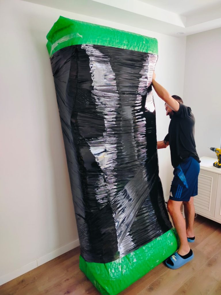 Streç film ve köşe koruyucuyla paketlenmiş dolap
